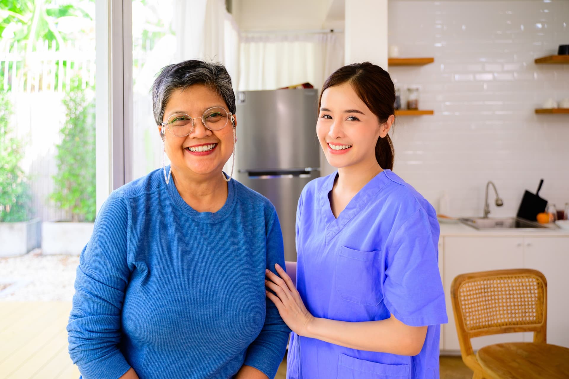 Cuidadora y señora mayor sonriendo en la cocina de casa